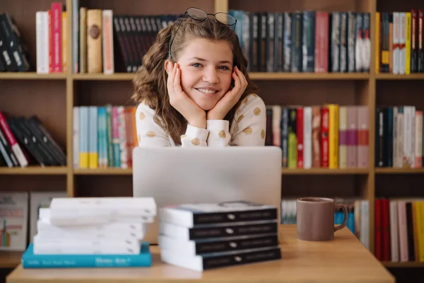 Girl studying among books using laptop — Stockfoto