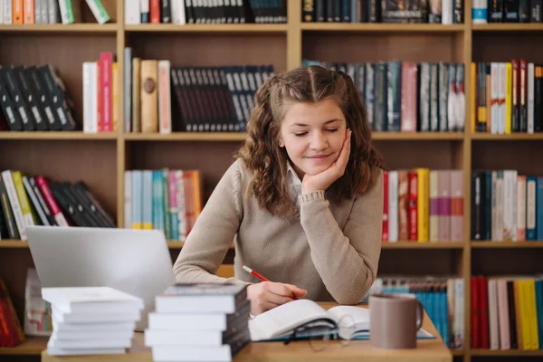 Girl studying among books using laptop — Foto de Stock