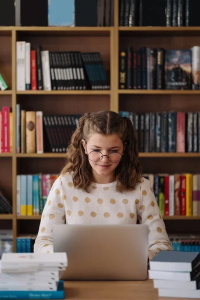 Girl studying among books using laptop ストックフォト