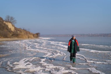 Otantik bir kadın donmuş gölde kış yürüyüşünün keyfini çıkarıyor.