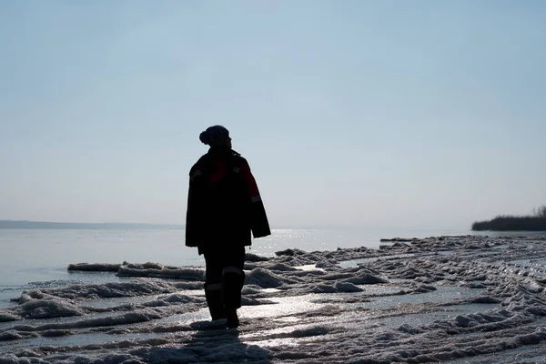 Женский силуэт, наслаждающийся зимней прогулкой по замерзшему озеру — стоковое фото