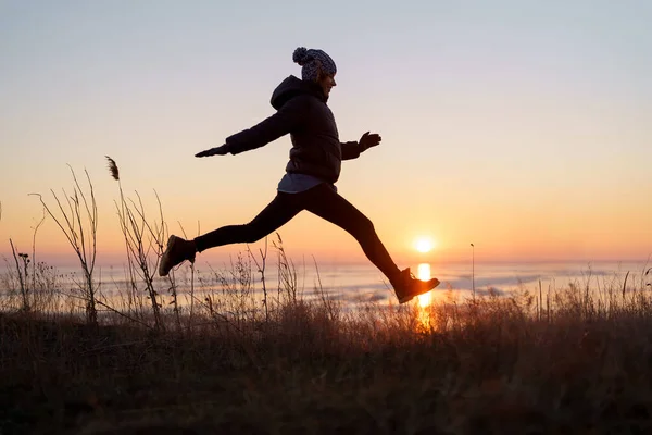 Motywacyjny wizerunek kobiety skaczącej w zachodzie słońca — Zdjęcie stockowe
