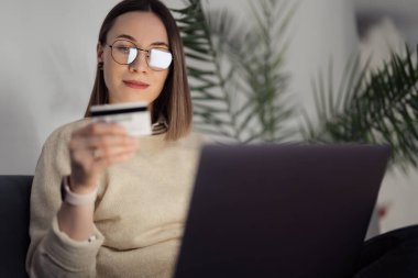 Kadın online alışveriş için dizüstü bilgisayar ve banka kartı kullanıyor