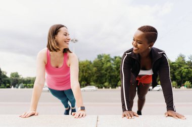 Spor faaliyetleri sırasında şehir meydanında tahta yapan iki güzel kadın.