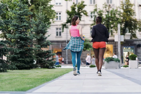 Dos chicas multiétnicas corriendo por las calles de la ciudad, comunicándose al aire libre. —  Fotos de Stock