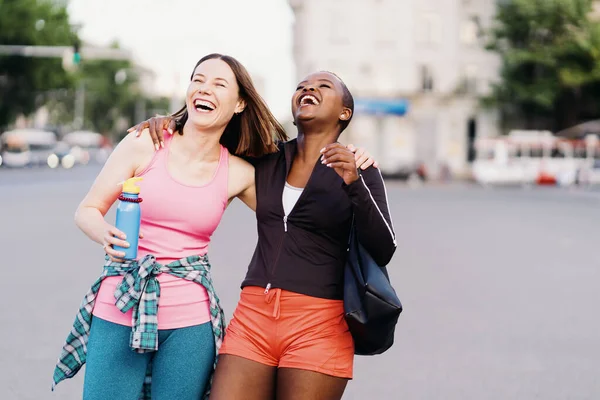 Dwie wielonarodowe dziewczyny spacerujące na sesję ćwiczeń, komunikacja na świeżym powietrzu. — Zdjęcie stockowe