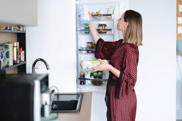Голодна жінка шукає їжу на кухні холодильника вдома — стокове фото