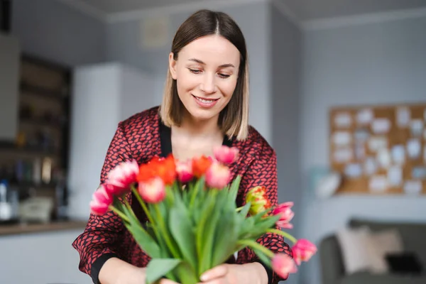 Χαμογελαστή γυναίκα απολαμβάνει τα λουλούδια στο σπίτι — Φωτογραφία Αρχείου