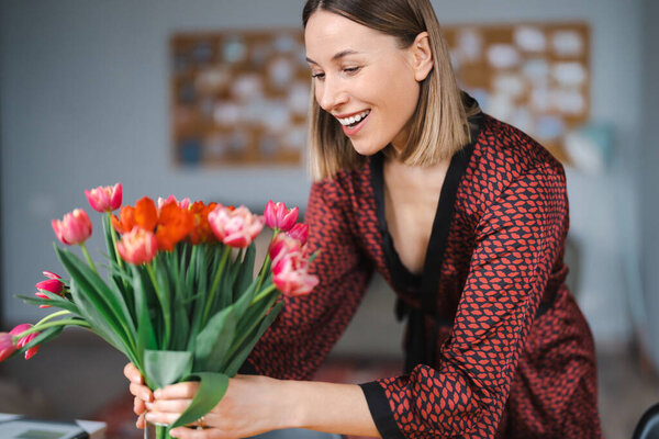 Smiling woman enjoy flowers at home