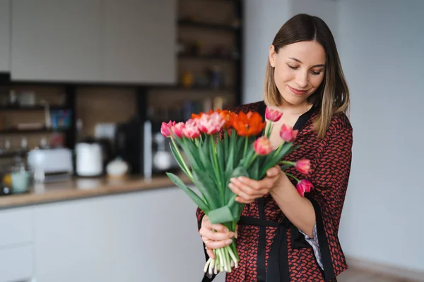 Jovem mulher gosta de flores em casa — Fotografia de Stock