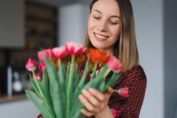 Młoda kobieta cieszyć kwiaty w domu — Zdjęcie stockowe
