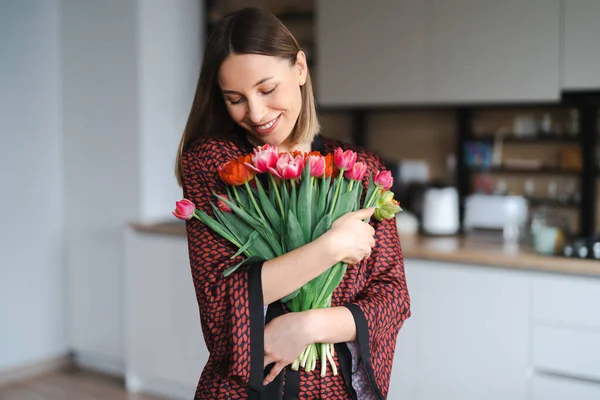 Jovem mulher gosta de flores em casa — Fotografia de Stock