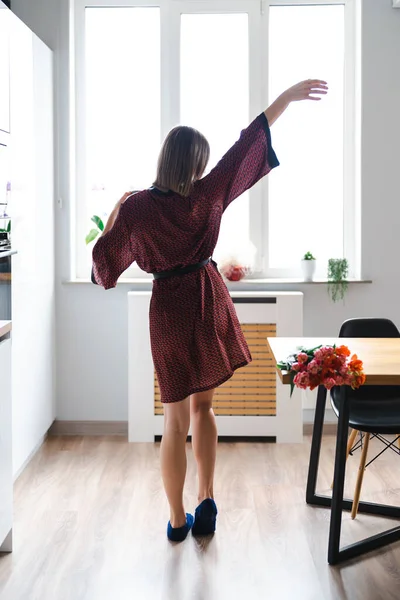 Mujer tomando un café en casa mientras baila y disfruta de las flores —  Fotos de Stock
