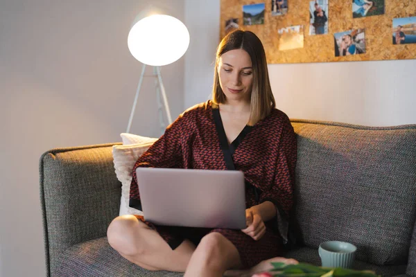 Жінка використовує ноутбук вдома розслабляючись — стокове фото