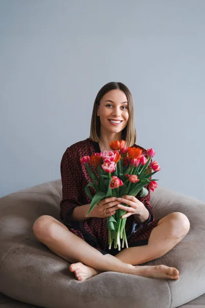 Młoda kobieta cieszyć się kwiaty w domu relaks na miękkiej torbie fasoli — Zdjęcie stockowe