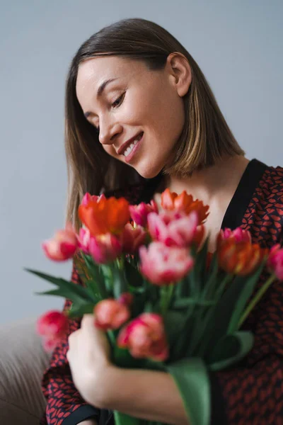 Mladá žena vychutnat květiny doma — Stock fotografie