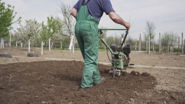 Άνθρωπος οργώνει τη γη στον κήπο στο φόντο του ουρανού — Αρχείο Βίντεο