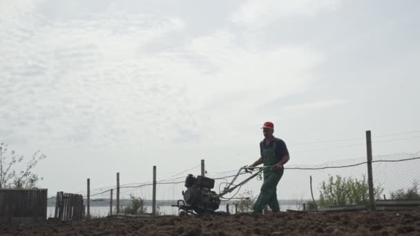 Homme labourant la terre dans le jardin sur fond de ciel — Video