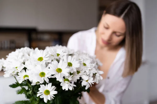 Belle femme mettant des fleurs blanches fraîches dans un vase — Photo