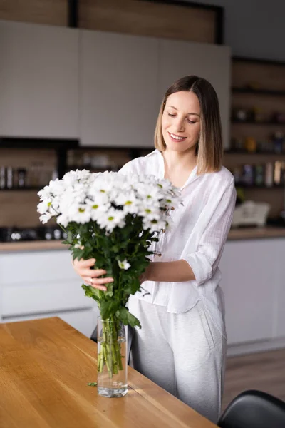 Красива жінка кладе свіжі білі квіти у вазу — стокове фото