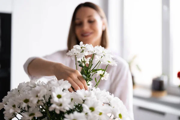 Belle femme mettant des fleurs blanches fraîches dans un vase — Photo
