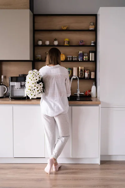 Mooie vrouw gieten water in een vaas in de keuken gootsteen om bloemen te plaatsen — Stockfoto