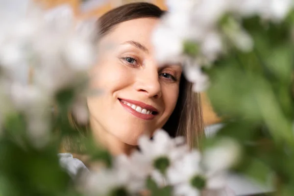 Donna sorridente che guarda attraverso fiori freschi — Foto Stock