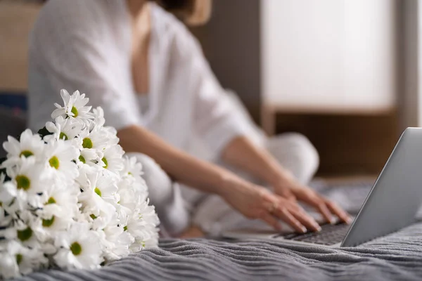 白い花の束と賭けに記載しながら、ラップトップを使用して通信する女性 — ストック写真