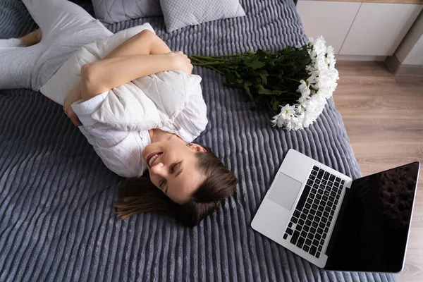 ベッドの上でラップトップを使用している間、女性はリラックスを楽しむ — ストック写真