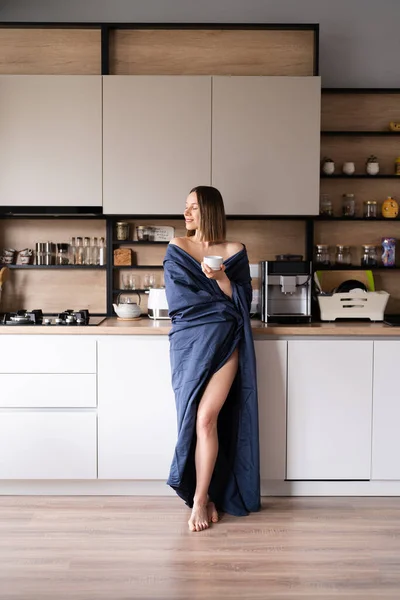 Сонная женщина пьет кофе по утрам на кухне — стоковое фото