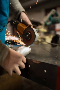 Kıvılcımlı metal üzerinde dairesel bir değirmenle çalışan bir işçi.