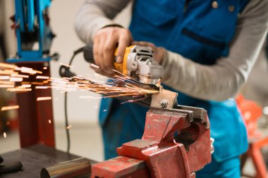 Kıvılcımlı metal üzerinde dairesel bir değirmenle çalışan bir işçi.