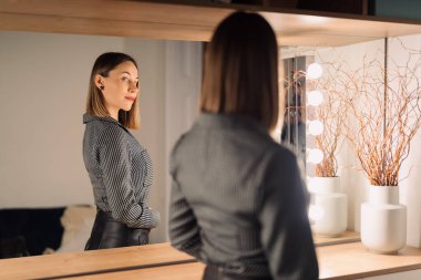 Güzel kadın aynadaki yansımasına bakıyor.