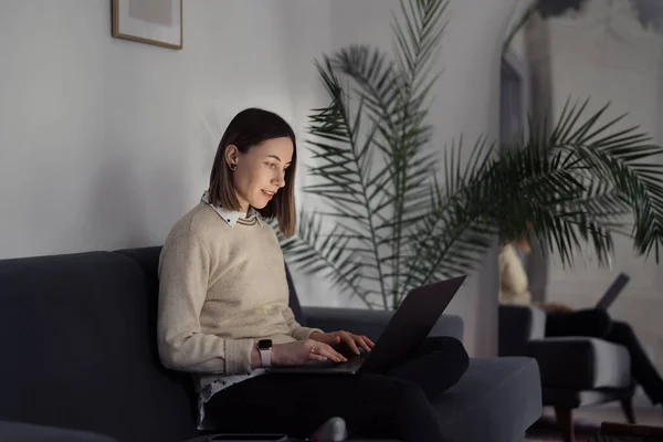 Жінка використовує ноутбук вдома у вітальні — стокове фото