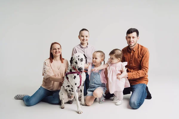 Family playing with a dalmatian dog on white background