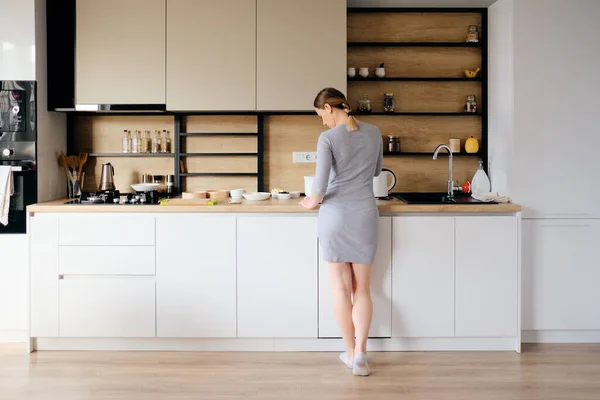 Achteraanzicht van de vrouw die naast een moderne keuken staat — Stockfoto
