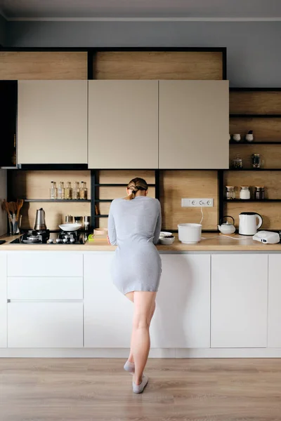 Achteraanzicht van de vrouw die naast een moderne keuken staat — Stockfoto