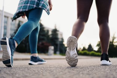 Arkadaşların spor giyim kuşamında arka planı şehirde koşuyor. Çok ırklı kadınlar spor yapıyor..