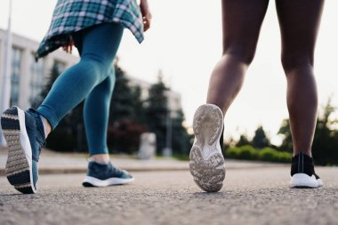 Arkadaşların spor giyim kuşamında arka planı şehirde koşuyor. Çok ırklı kadınlar spor yapıyor..