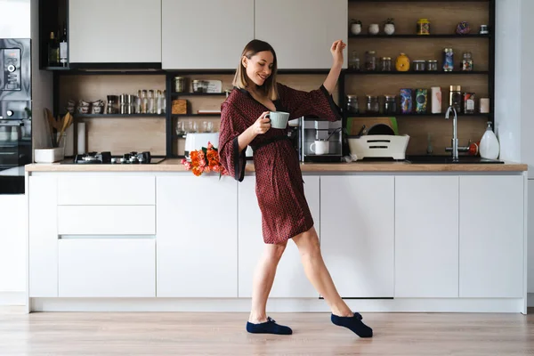 Счастливая Женщина Выпивающая Кофе Дома Танцующая Расслабляющаяся Кухне Шелковом Халате — стоковое фото