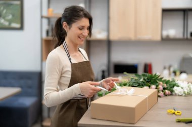 Çiçeklerle atölyesinde çalışan bir kadın sipariş üzerine kompozisyon kutusu yapıyor.