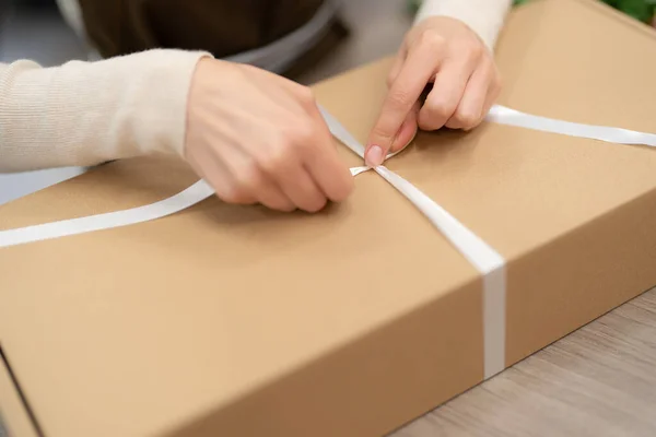 Woman hands wrapping a present in a box while working in the shop