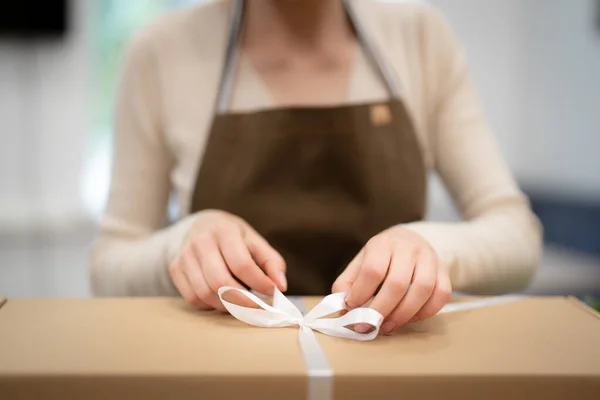 Woman hands wrapping a present in a box while working in the shop