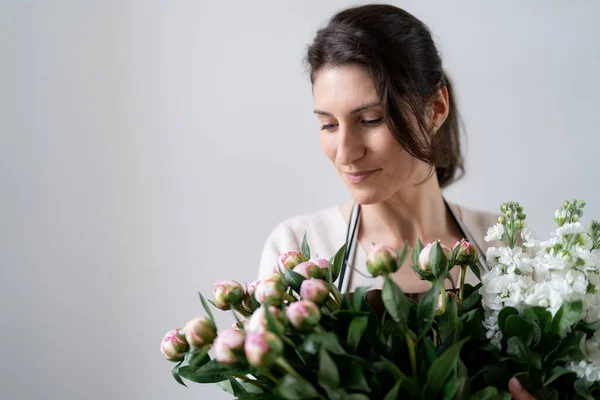 女性花屋室内の白い背景に白とピンクの花の束を埋め込む — ストック写真