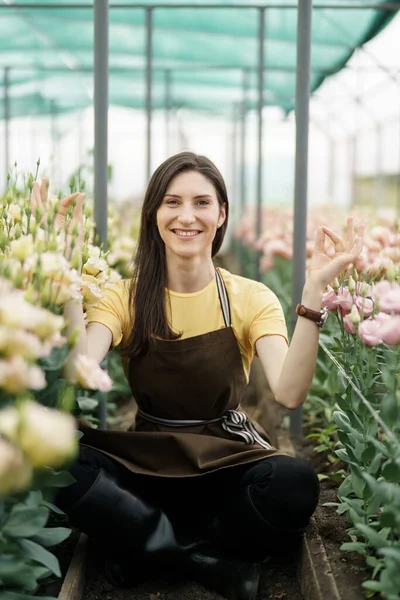 Pretty women relaxing among flowers while sitting in a meditation pose in the green house