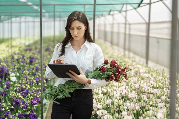 Fresh flowers delivery, women taking order on the tablet. Businesswoman using technologies in her flower business.