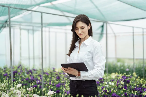 Fresh flowers delivery, women taking order on the tablet. Businesswoman using technologies in her flower business.