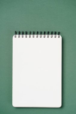 Kağıt yeşili arka planda okul defteri, sarmal not defteri ve karton kalem.