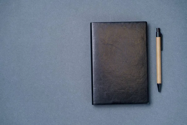 Black leather notebook on a paper gray background, notepad mock up, top view shot