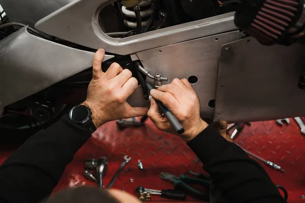 Repairman repair motorcycle, maintenance in garage. Mechanic fixing bike in a modern shop